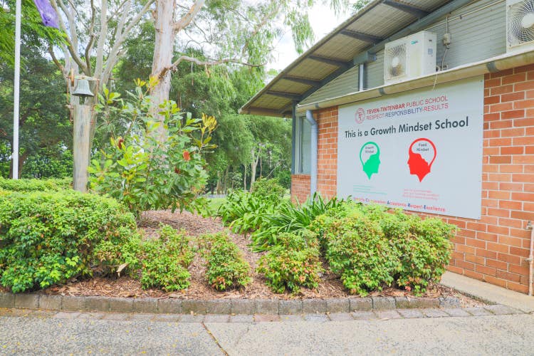 Front of school, bush and wall with sign saying 'This is a Growth Mindset School'